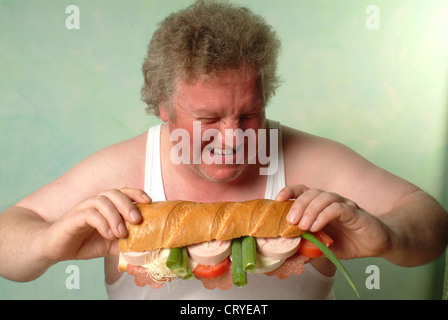 Fetter Mann im Unterhemd Essen eine große baguette Stockfoto