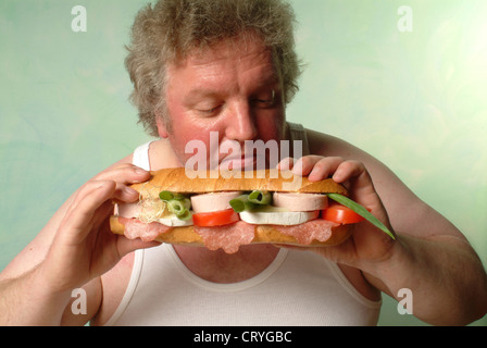 Fetter Mann im Unterhemd Essen eine große baguette Stockfoto