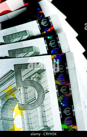 Nahaufnahme des Wertpapier- und Sicherheitshologramms auf einem offenen Stapel von 5-Euro-Banknoten auf schwarzem Hintergrund. Stockfoto