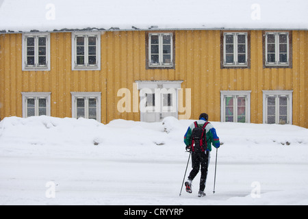 Mann mit Wanderstöcken übergibt traditionellen Holzhäuser auf Storgata in malerische Gegend von Polarkreis, Tromsø, Nordnorwegen Stockfoto