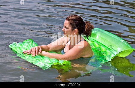 Eine Frau auf einem bunten Schwimmer im Wasser entspannen. Stockfoto