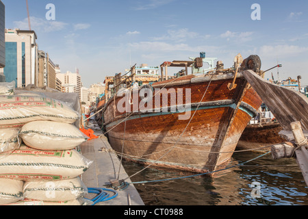 Dhau vertäut am Dubai Creek, Dubai, Vereinigte Arabische Emirate mit Säcken Fracht am Kai Stockfoto