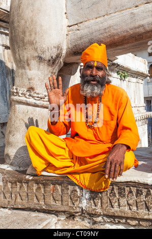Sadhu, indisch-hinduistischen heiligen Mann gekleidet in traditionellen Safran Roben geben einen Segen für Almosen außerhalb Jagdish Tempel in Udaipur, Rajasthan, Indien Stockfoto