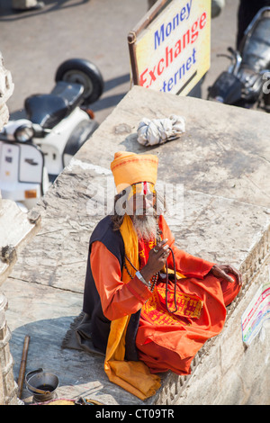 Sadhu, indisch-hinduistischen heiligen Mann, gekleidet in traditionellen Safran Roben sitzen, geben einen Segen vor Jagdish Tempel in Udaipur, Rajasthan, Indien Stockfoto