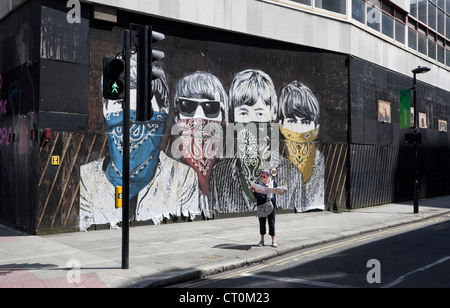 Eine Touristin, die eine Karte vor dem Beatles-Wandbild liest, Museum Street, London England, Großbritannien. Stockfoto