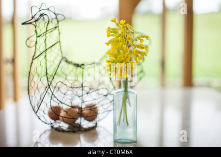 Eiern in Draht Henne Ornament und Vase mit wilden Schlüsselblumen, Primula Veris, im Frühling in den Cotswolds, Oxfordshire, Vereinigtes Königreich Stockfoto