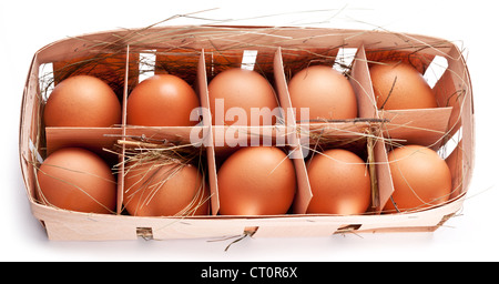 Eiern mit einem Strohhalm in einem hölzernen Korb auf einem weißen Hintergrund. Stockfoto