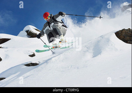 Skifahrer vom verschneiten Hang springen Stockfoto
