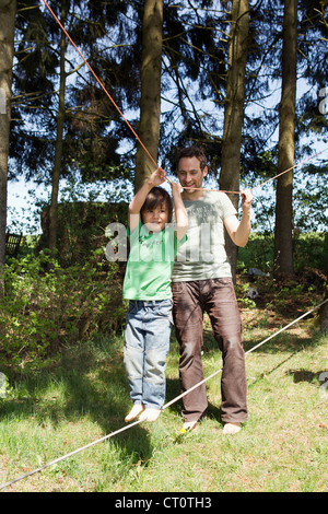 Vater Sohn auf Drahtseil gehen zu helfen Stockfoto