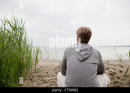 Mann sitzt am Sandstrand Stockfoto