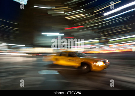 Bewegung verwischt Bild von einem gelben New York Taxi fahren in Manhattan bei Nacht. Stockfoto