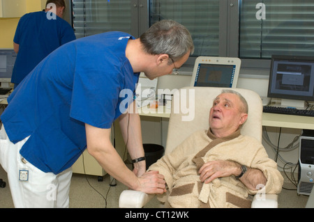 Ein älterer Mann sitzen und im Gespräch mit einem Arzt nach einer endoskopischen Verfahren. Stockfoto