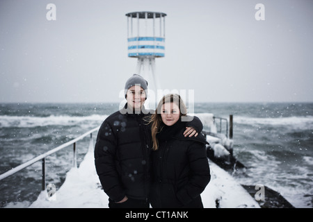 Paar umarmt auf verschneiten pier Stockfoto