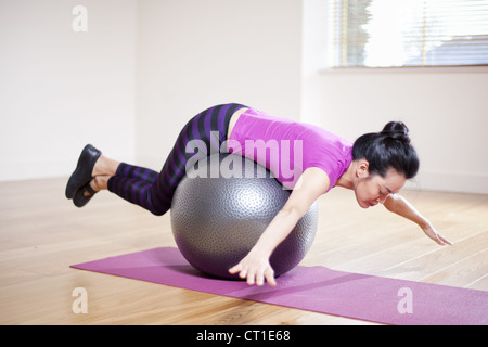 Frau balancieren auf Ball im Yoga-studio Stockfoto