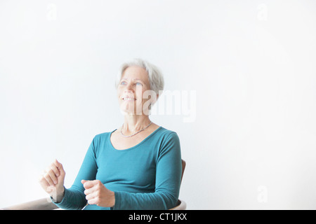 Lächelnde ältere Frau im Sessel sitzen Stockfoto