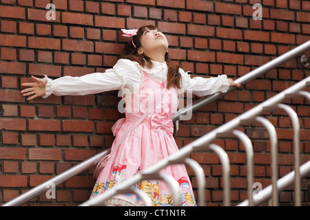 japanische Lolita Cosplay Ziegelwand gelehnt, auf Treppen Stockfoto