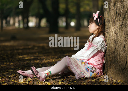 traurig japanische Lolita gelehnt Baum im park Stockfoto