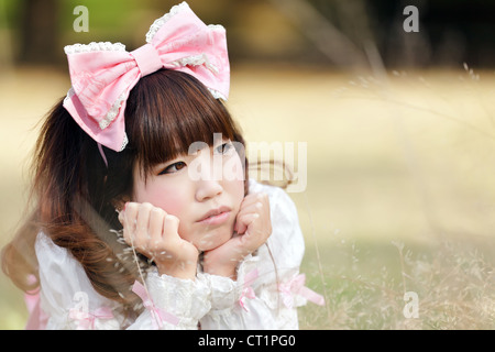 Japanerin in süßen Lolita cosplay liegend auf Wiese, Tokio Stockfoto