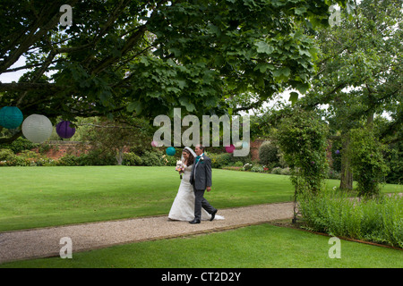 Braut und ihr Vater Fuß einen ummauerten Garten Weg, während eine standesamtliche Trauung in Essex. Stockfoto