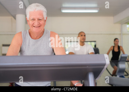 Menschen und Sport, älterer Mann arbeiten auf Laufband im Fitness-Studio unter Jugendlichen Stockfoto