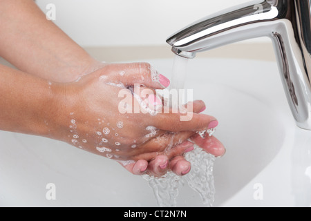 Frau wäscht Hände mit Seife und Wasser unter Wasserhahn im Badezimmer Stockfoto
