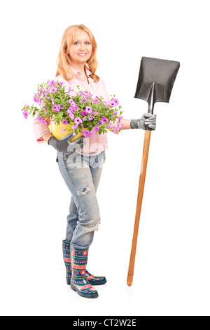 In voller Länge Portrait von einem weiblichen Gärtner halten Blumen und eine Schaufel, die isoliert auf weißem Hintergrund Stockfoto