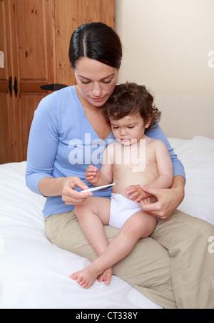 Mama, die Temperatur des Babys mit Windpocken zu lesen Stockfoto