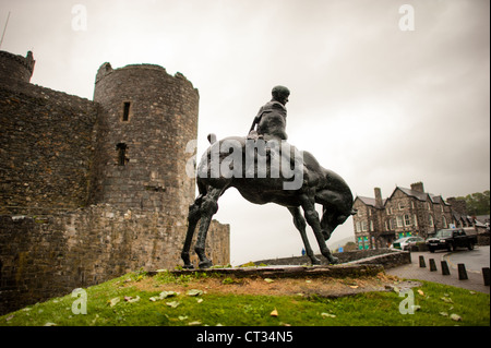 Zwei-Könige-Statue Harlech Castle Bronzeskulptur Harlech Vereinigtes Königreich | HARLECH, Wales — Die Bronzeskulptur Die zwei Könige von Ivor Roberts-Jones aus dem Jahr 1984 steht vor den Steintürmen von Harlech Castle. Das Kunstwerk zeigt den Riesen Bendigeidfran, der das Kind Gwern trägt, eine Szene aus dem walisischen Mythologiezyklus der Mabinogion. Die Platzierung dieses Denkmals für die walisische Legende direkt vor einer Festung, die von Eduard I. zwischen 1283 und 1289 erbaut wurde, schafft einen bewussten Kontrast zur Geschichte der englischen Eroberung der Region. Stockfoto