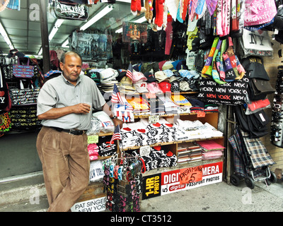 Indische Händler steht vor seinem Geschäft mit Anzeige von New York Souvenir waren auf der 8th Avenue Midtown Manhattan Stockfoto