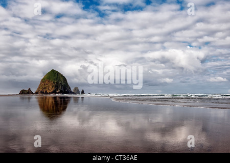 Morgen Ebbe Reflexionen von Haystack Rock und obenliegende Wolken auf Oregons Cannon Beach. Stockfoto
