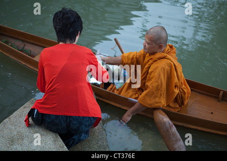 Thai Mönch Reisen von Tempel zu Tempel und sammeln Sie Almosen auf ihre Runden am Morgen mit dem Boot in Amphawa. Stockfoto