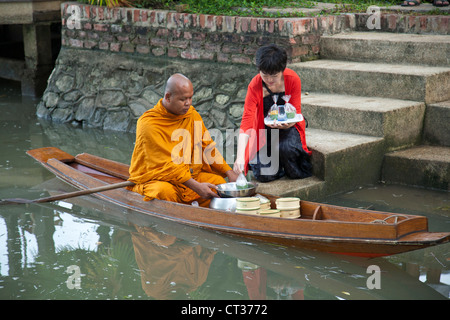 Thai Mönch Reisen von Tempel zu Tempel und sammeln Sie Almosen auf ihre Runden am Morgen mit dem Boot in Amphawa. Stockfoto