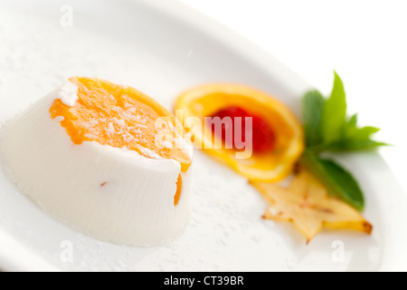 Italienisches Dessert Pannacotta auf weißen Teller dekoriert mit Kokosmilch und Pfirsich. Stockfoto