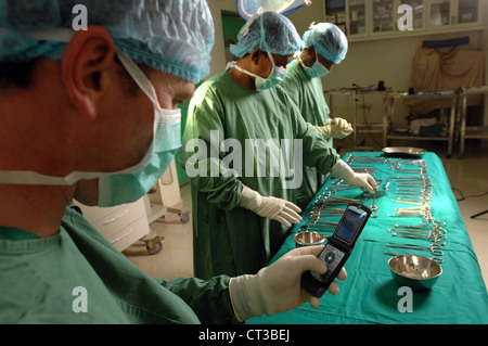 Chirurgische Theater Personal verschiedene chirurgische Werkzeuge auf dem OP-Tisch auslegen, während der Chirurg sein Handy überprüft. Stockfoto