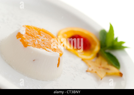 Italienisches Dessert Pannacotta auf weißen Teller dekoriert mit Kokosmilch und Pfirsich. Stockfoto