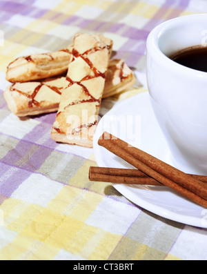 Kaffeetasse, Zimt, Süßigkeiten auf der Tischdecke Stockfoto