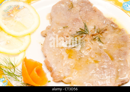 Kalbsschnitzel mit Zitronensauce in einem dekorierten Teller. Stockfoto