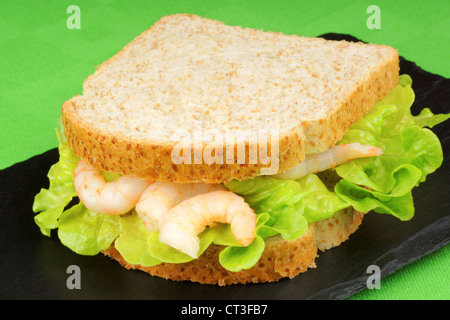 Garnelen-Sandwich mit Salat auf einem Schiefer Tablett über eine grüne Tischdecke Stockfoto