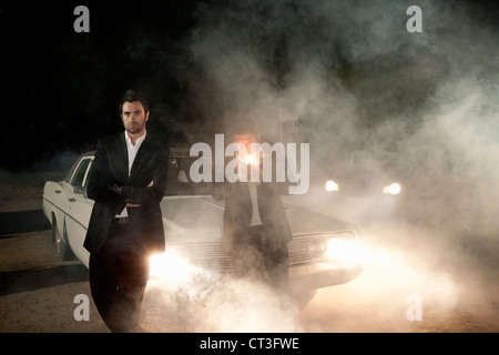 Männer in Anzügen, die mit dem Auto im Nebel warten Stockfoto