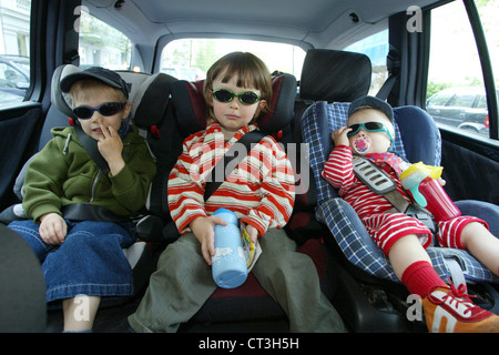 Berlin, drei Kinder, die ihre Kindersitze im Auto angeschnallt Stockfoto