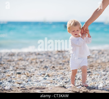 Baby Mütter Hand hält und zu Fuß am Strand Stockfoto