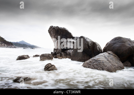 Wellen über die Felsen am Strand Stockfoto