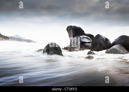 Wellen über die Felsen am Strand Stockfoto