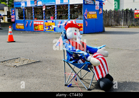 Eine aufblasbare lebensgroße Uncle Sam-Figur sitzt auf einem Stuhl vor einer Feuerwerk-Tribüne mit patriotischen Charme und Reiz. Stockfoto
