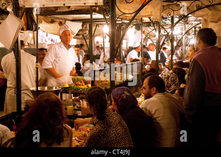 Menschen essen Street Food an den Imbissständen in Djemaa el Fna Square bei Nacht, Marrakesch Marokko Afrika Stockfoto