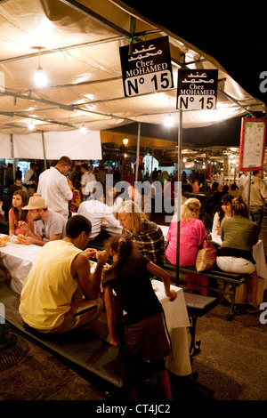 Touristen Essen an Ständen in der Djemaa el Fna Square bei Nacht, Marrakesch Marokko Afrika Stockfoto