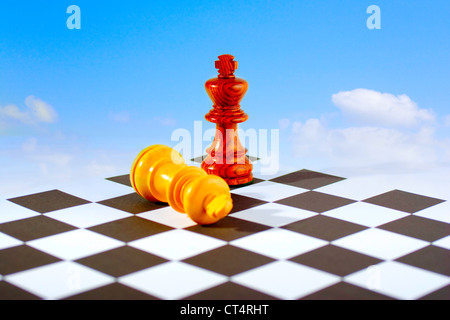 Zwei Schach-Könige an Bord, ein stehend, eine liegend, blauem Himmel und weißen Wolken Hintergrund Stockfoto