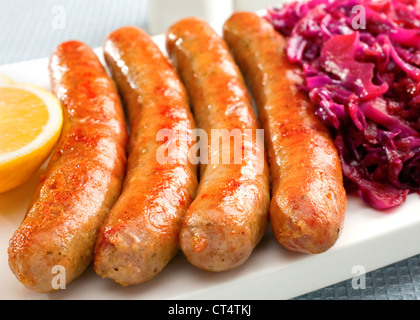 Eine Platte mit deutschen Thüringer Würstchen oder Bratwurst mit gewürzter Rotkohl und Zitrone. Stockfoto