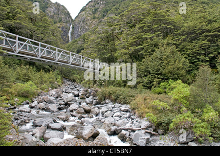 Gang über einen Bach in Arthurs Pass, mit dem Teufel Punchbowl fällt in der Ferne. Stockfoto