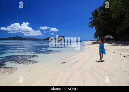 Frau in blau Sarong zu Fuß entlang des Strandes in der Nähe von Anse Source d ' Argent auf La Digue auf den Seychellen Stockfoto